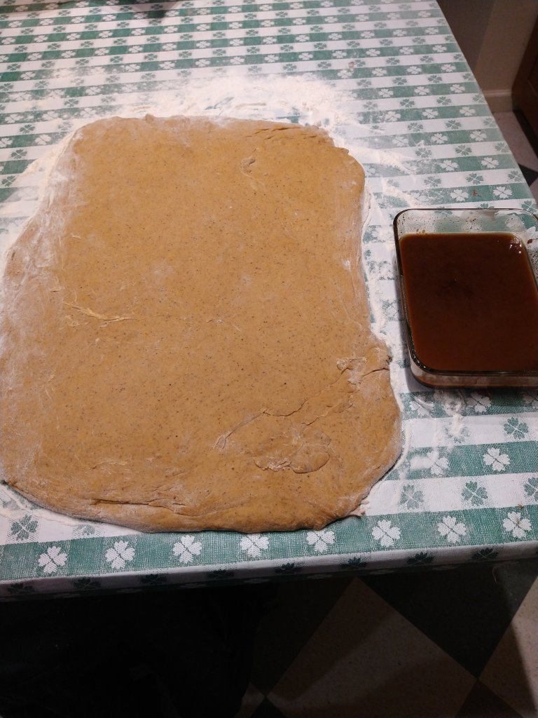 Picture of spread out cinnamon roll dough and the spice syrup spread.